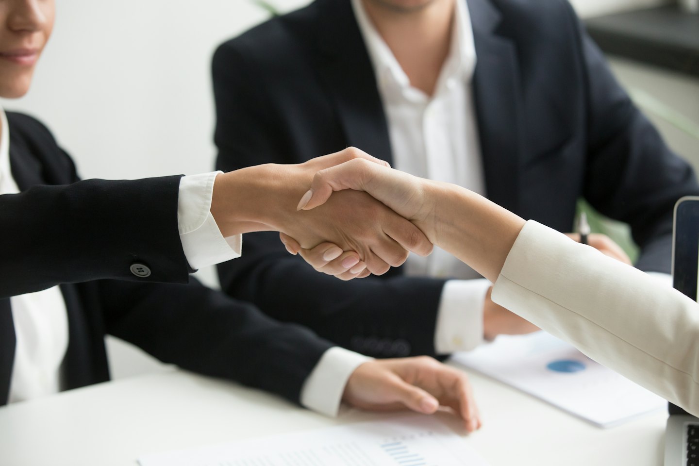 Due professionisti si stringono la mano su una scrivania in un ufficio.